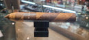 A single Macanudo Espresso cigar resting on a black stand, with its wrapper displaying a distinctive brown and white striped pattern.