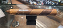A single Macanudo Espresso cigar resting on a black stand, with its wrapper displaying a distinctive brown and white striped pattern.
