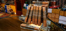 A display of several packaged Oliva Robusto Serie G cigars wrapped in clear plastic with dark paper bands, arranged on a glass countertop inside a retail store.