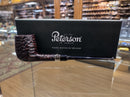 A Peterson smoking pipe with a dark textured bowl and long dark stem, displayed in front of a black Peterson of Dublin box on a glass display case inside a shop.
