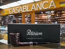 A Peterson of Dublin smoking pipe with a dark textured bowl and black handle, displayed in front of a black branded box on a counter, with a blurred Casablanca shop interior in the background.