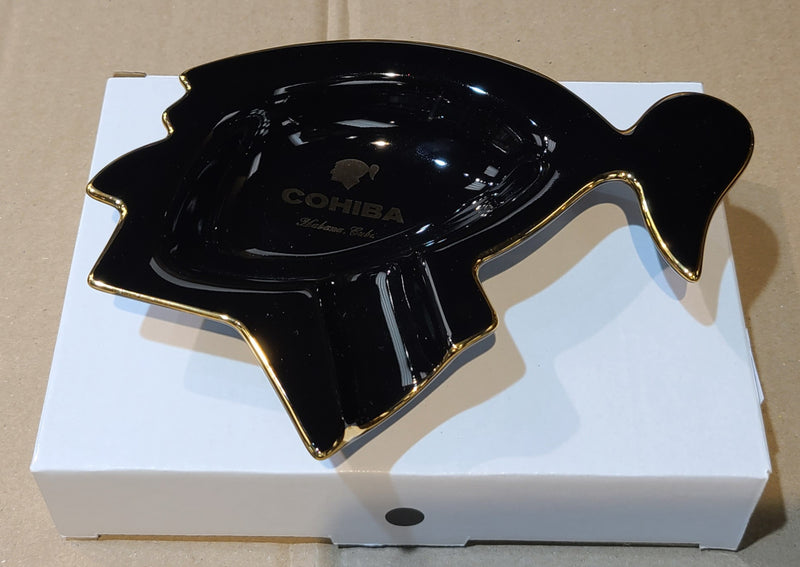 A black and gold Cohiba single cigar ashtray with a sculptural design, placed on a white box.


