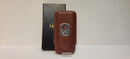 A brown 3 cigar holder with a stainless steel cutter, displayed in front of its packaging.